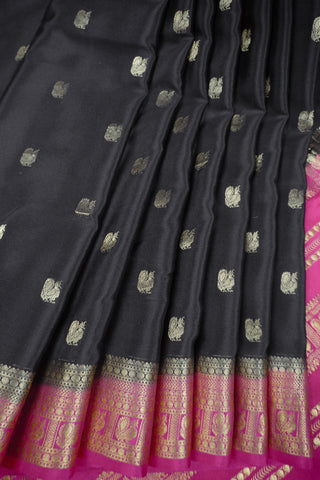Black crepe silk saree with scattered gold peacock buttis, magenta pink border and zari striped pallu