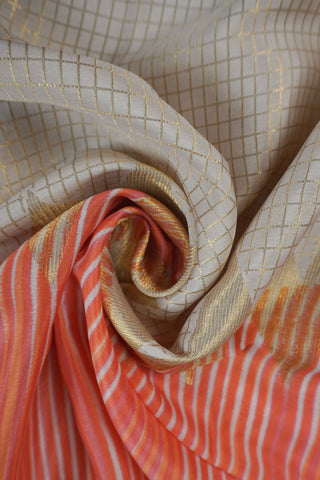 Ivory saree with gold zari checks, coral pink stripes and a triangular zari pattern leading into the pallu