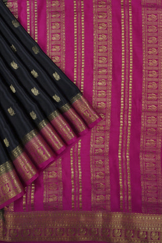 Black crepe silk saree with scattered gold peacock buttis, magenta pink border and zari striped pallu