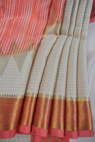 Ivory saree with gold zari checks, coral pink stripes and a triangular zari pattern leading into the pallu