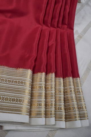 Maroon crepe silk saree with gold zari geometric border and an off-white pallu with vertical zari stripes