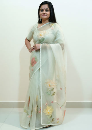 Pearl white tissue organza saree with 3D floral embroidery and lace scallop border.