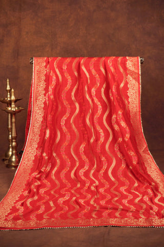 Red art silk dupatta with wavy gold zari leheriya lines, pink and orange meenakari vines and gold kiran lace edging