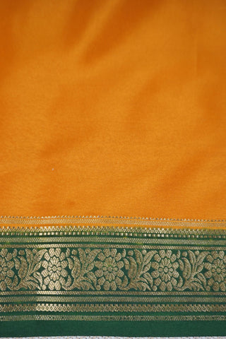 Mustard yellow silk saree with a bottle green border woven in gold zari floral and leaf motifs, striped pallu