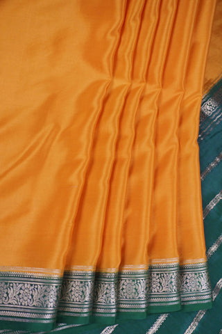 Mustard yellow silk saree with a bottle green border woven in gold zari floral and leaf motifs, striped pallu