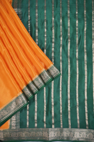 Mustard yellow silk saree with a bottle green border woven in gold zari floral and leaf motifs, striped pallu