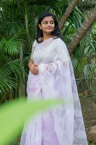 Light lilac tissue organza saree with floral applique, pearls, sequins, and scallop border.