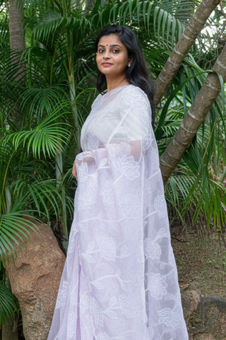 Light lilac tissue organza saree with floral applique, pearls, sequins, and scallop border.