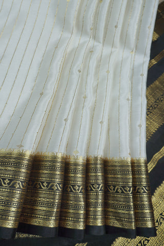 Ivory silk saree with gold pinstripes, a black zari lattice border with temple edges and a black striped pallu