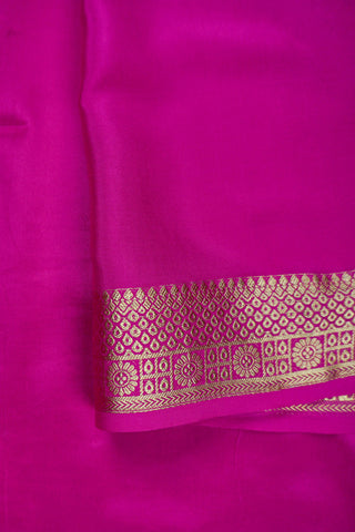 Magenta pink crepe silk saree with scattered gold zari dots and a floral rosette border with lattice bands