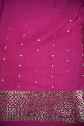 Magenta pink crepe silk saree with scattered gold zari dots and a floral rosette border with lattice bands