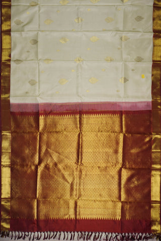Off white Kanjivaram silk saree with gold zari paisley motifs and a deep maroon full brocade pallu