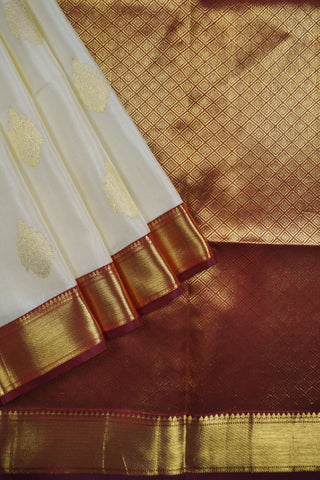 Off white Kanjivaram silk saree with gold zari paisley motifs and a deep maroon full brocade pallu